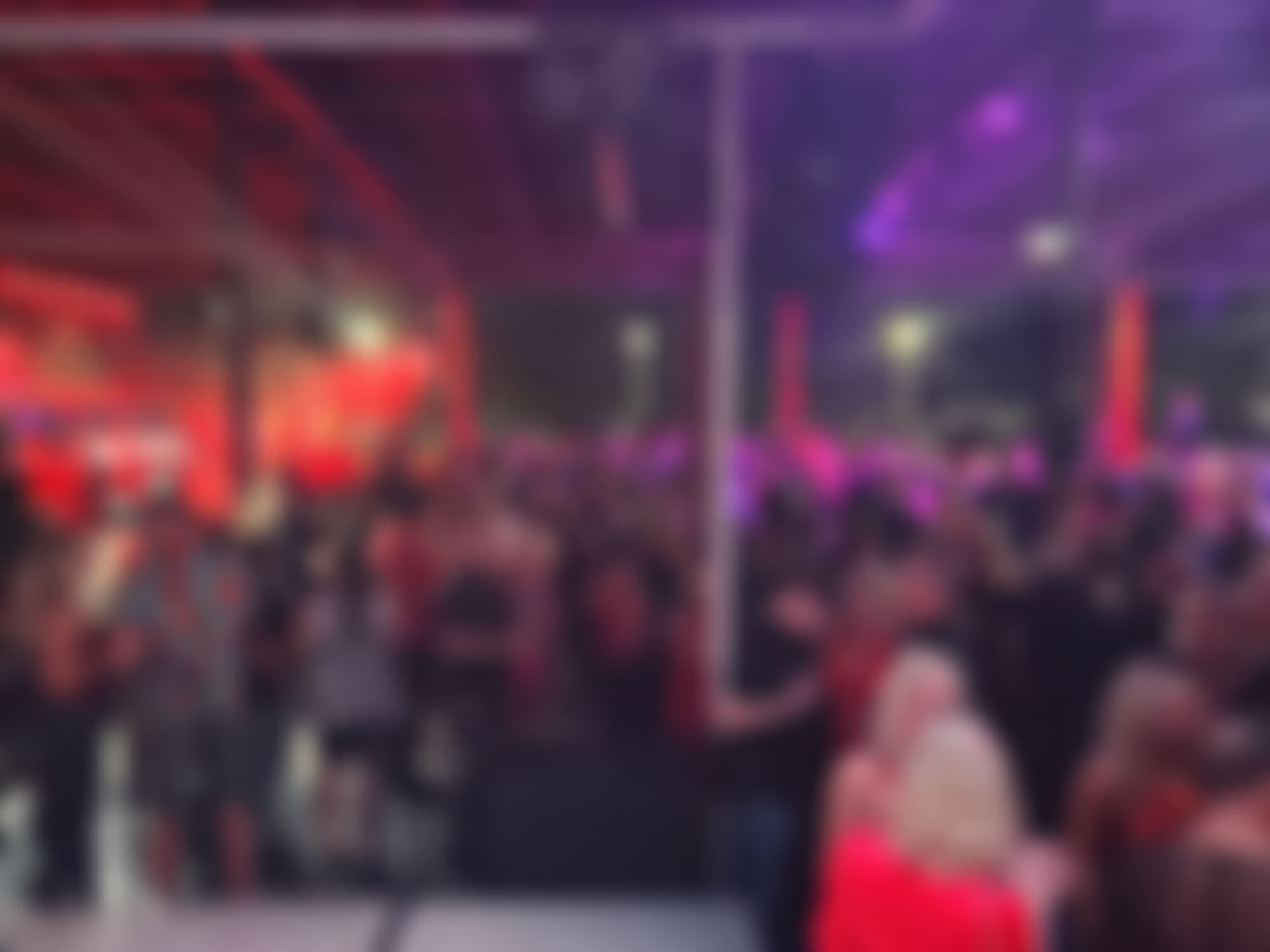 A TampArotic dancefloor under red truss lighting, live band — crowd blurred for privacy