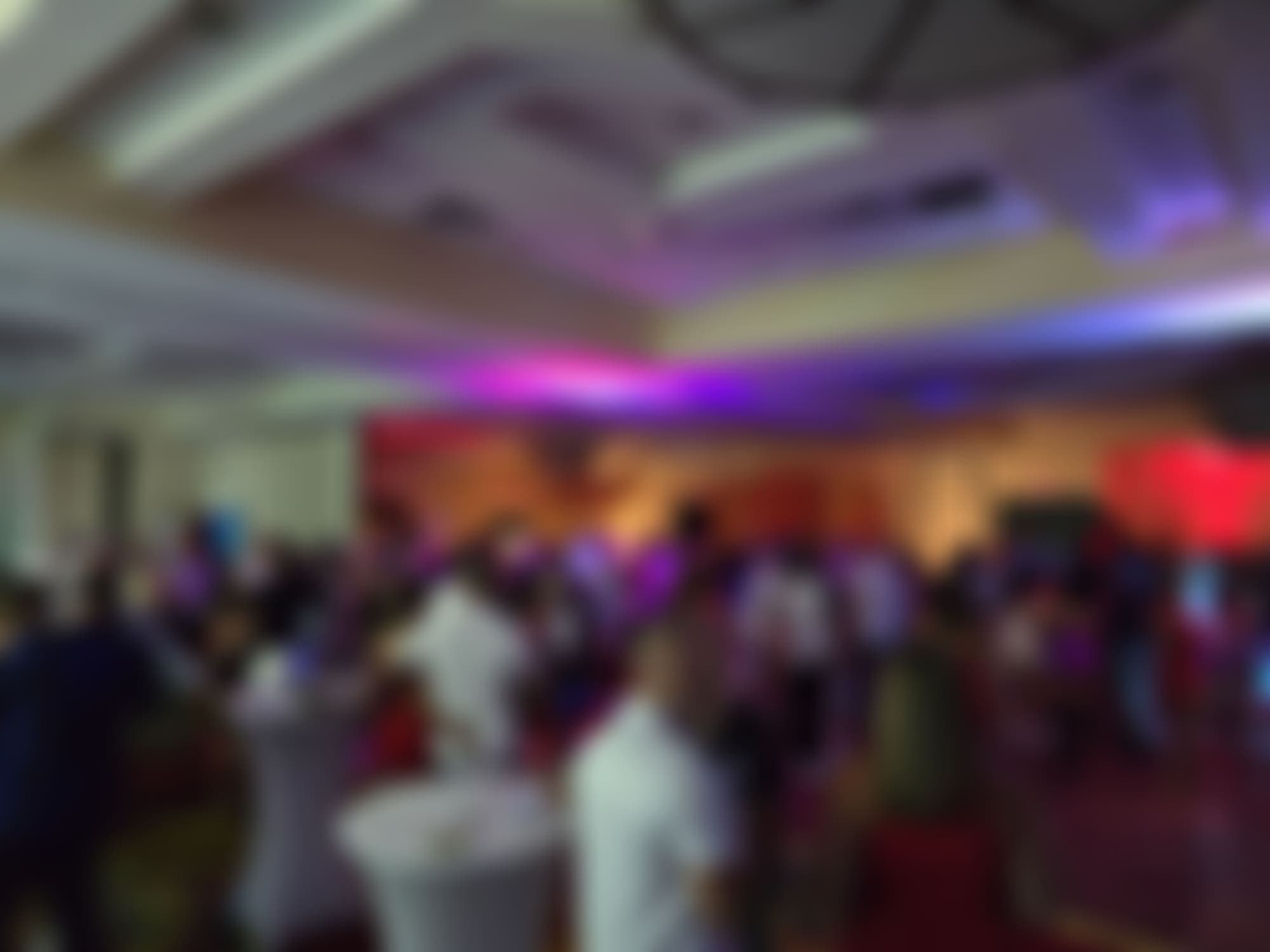 A packed TampArotic ballroom at peak, awash in blue and magenta light — guests blurred for privacy